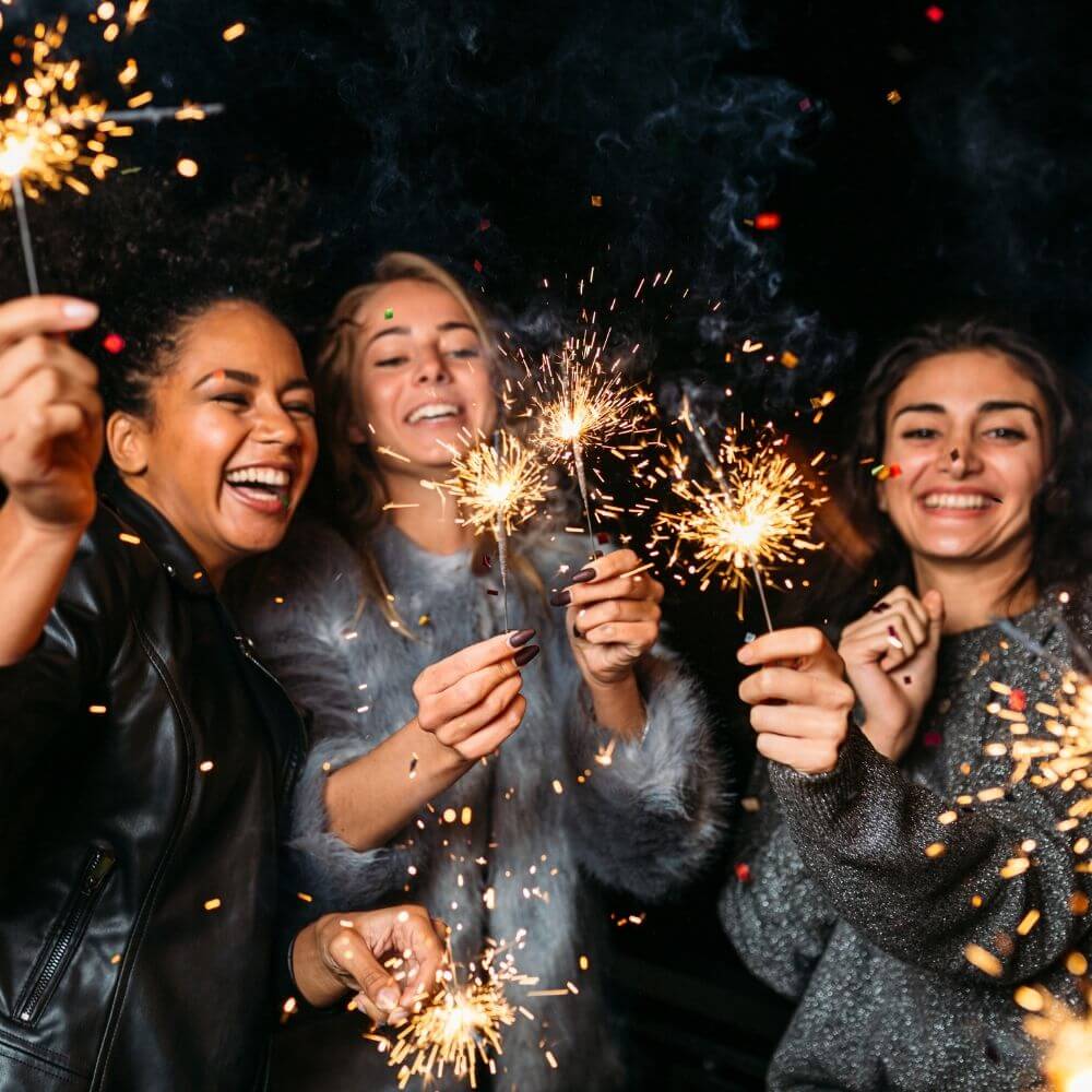 Füllbild: Mehrere Frauen stehen mit gezündeten Wunderkerzen im Kreis und lachen.