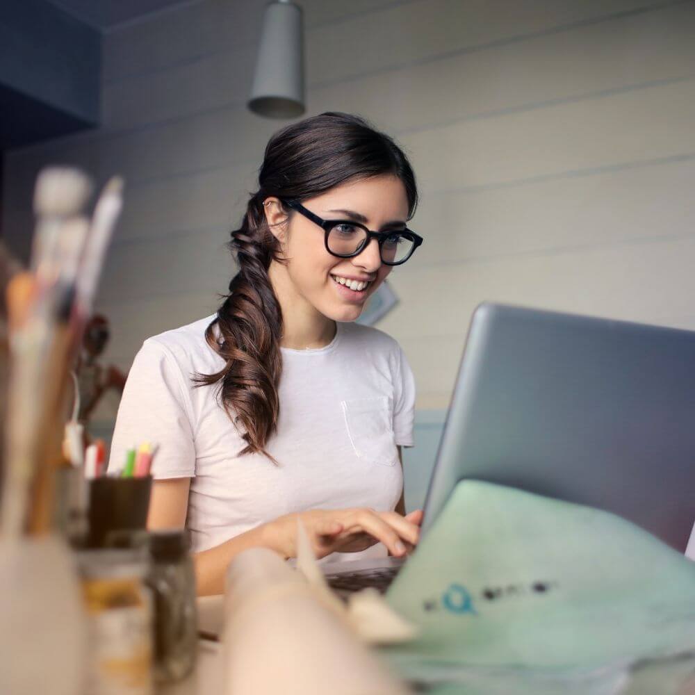 Füllbild: Frau mit Brille sitzt angeregt vor einem Laptop.