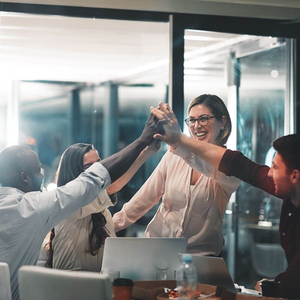 Füllbild: Arbeitsgruppe schlägt sich gemeinsam über dem Tisch ab.