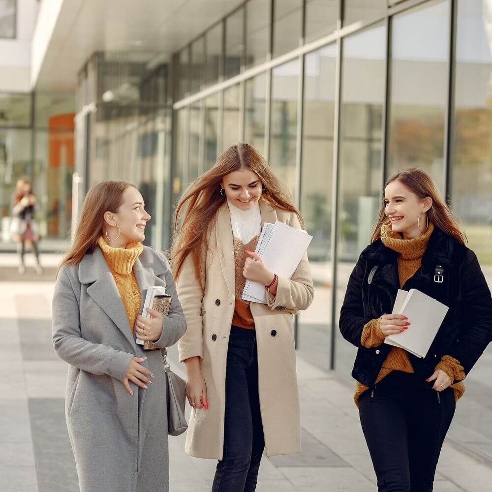 Füllbild: Drei junge Frauen mit Papieren in der Hand vor öffentlichem Gebäude.